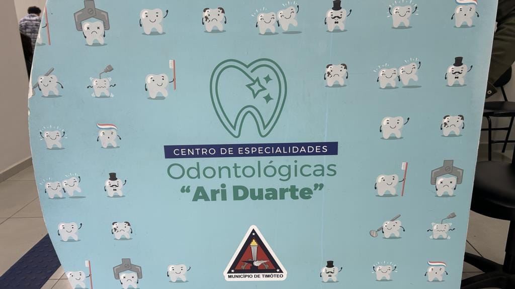 Painel azul do Centro de Especialidades Odontológicas Ari Duarte, com desenhos de dentes e o brasão de Timóteo